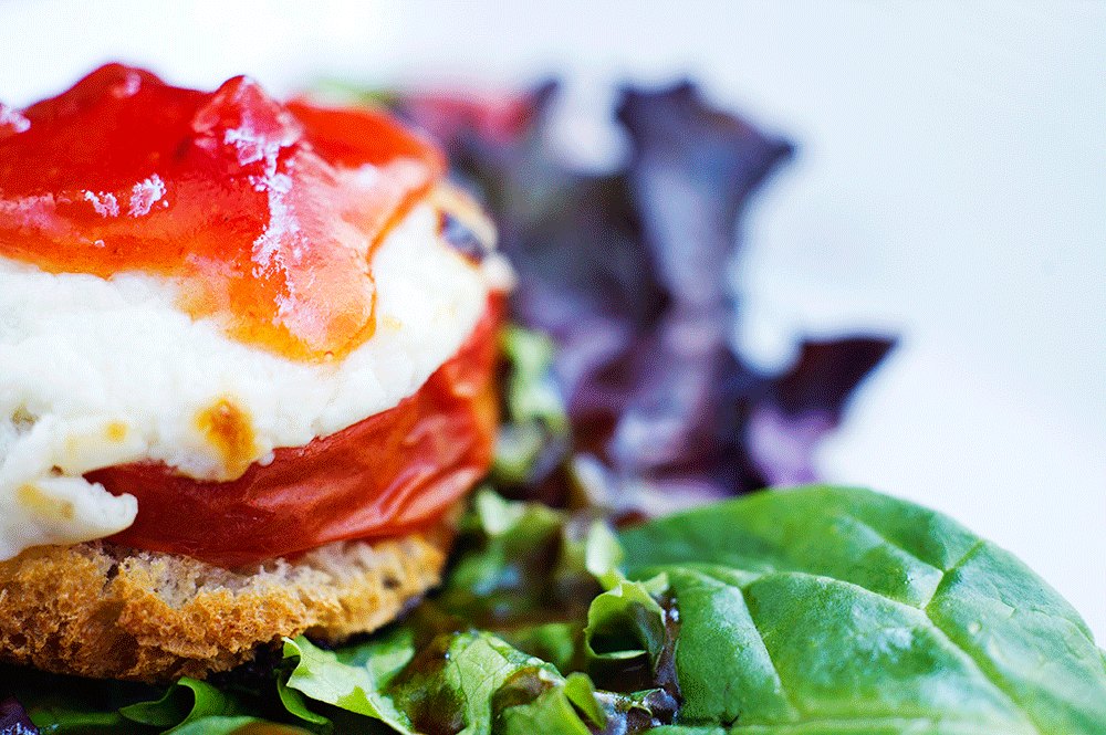 Torre de tomate con queso y mermelada sobre hojas verdes