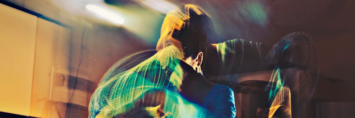 Bailaor flamenco en movimiento, con camisa verde y luces de colores