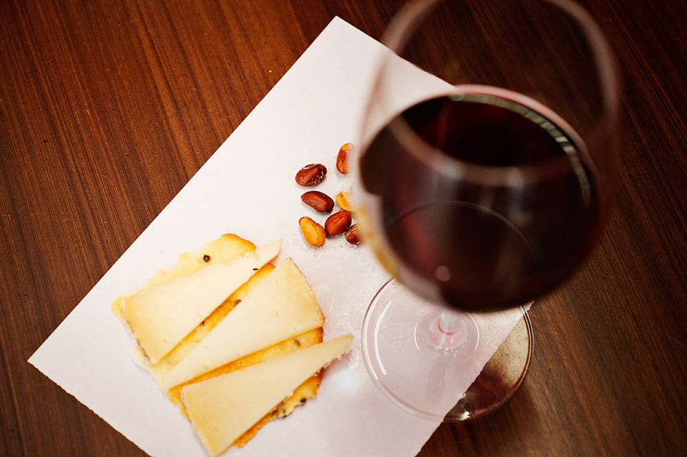 Copa de vino tinto con queso manchego y almendras