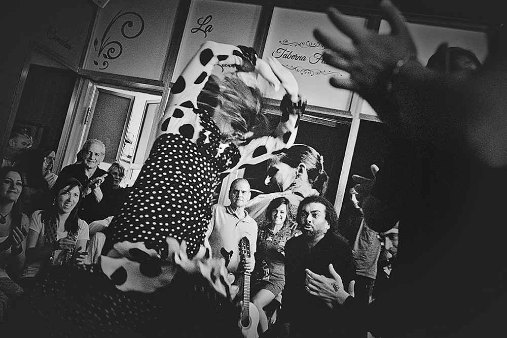 Bailaora con vestido de lunares bailando entre el público, en blanco y negro