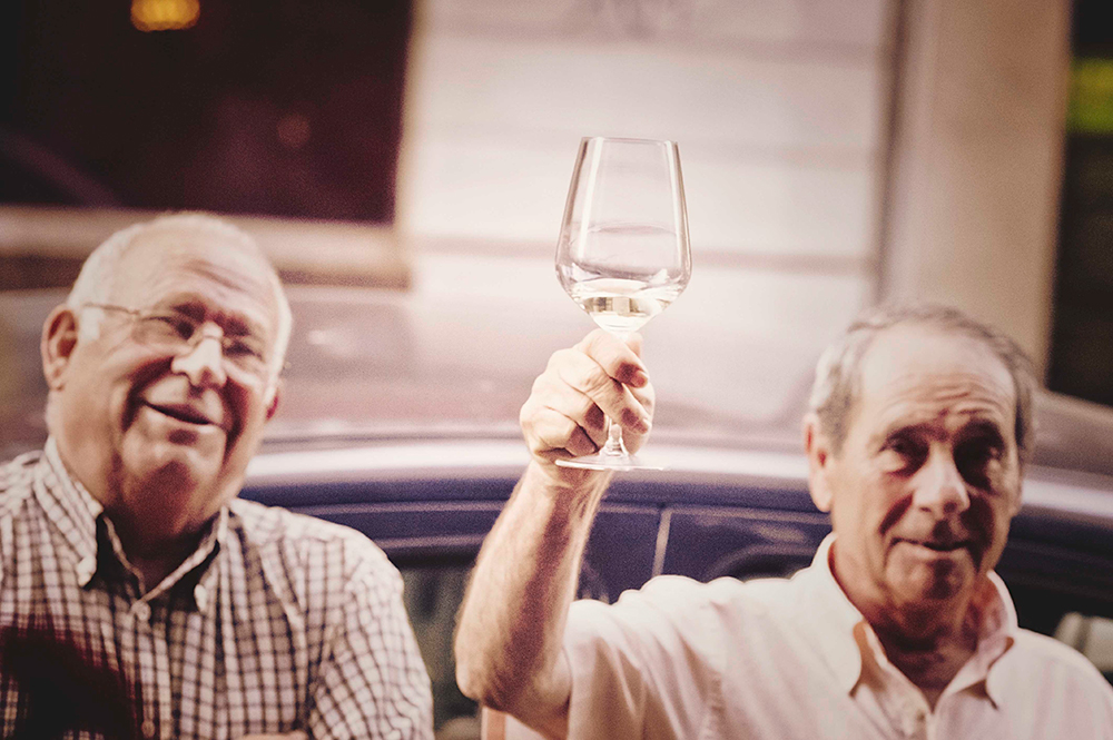 Cliente brindando con una copa de vino blanco