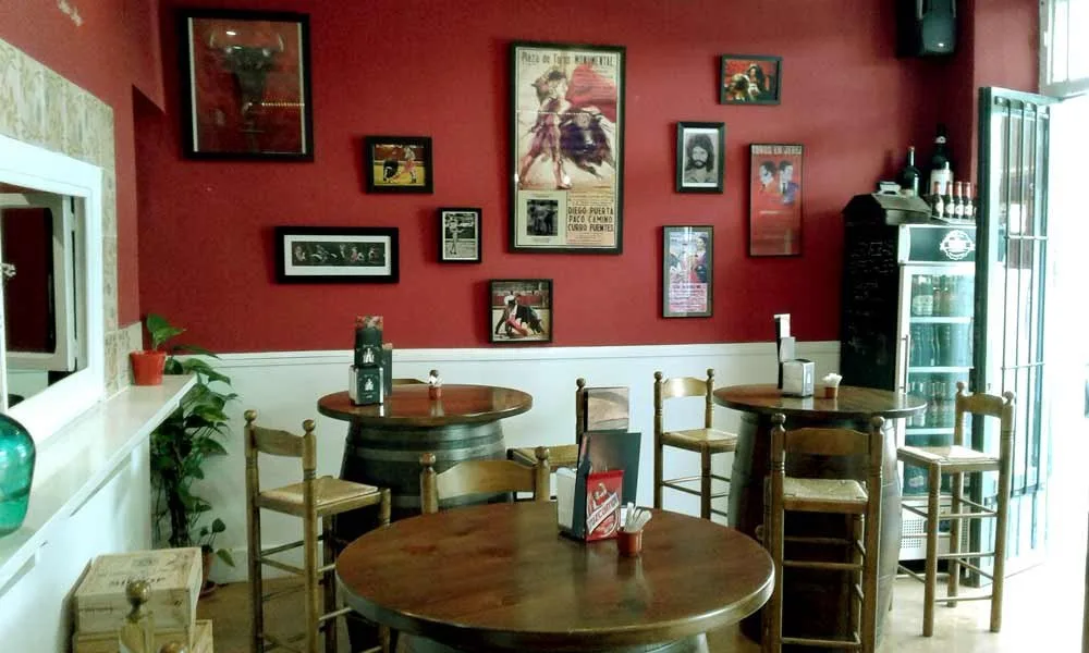 Sala de La Tasca del Arte con mesas altas, toneles y carteles flamencos