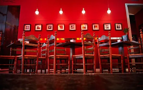 Sala de la taberna con taburetes rojos y cuadros flamencos en la pared